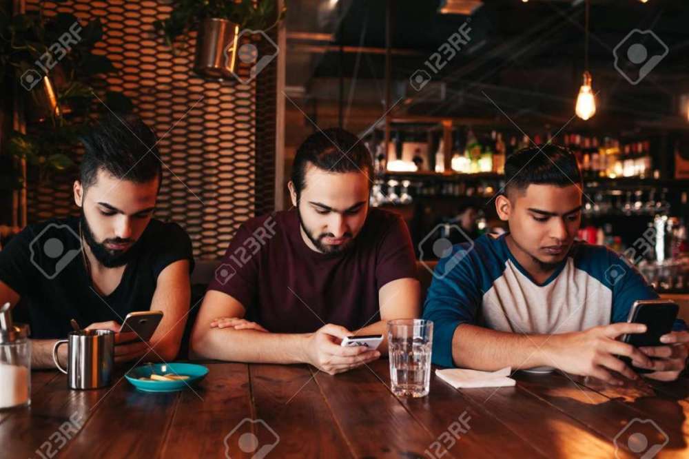 113819248-social-media-addiction-concept-mixed-race-friends-looking-at-their-phones-in-lounge-bar-loneliness.jpg